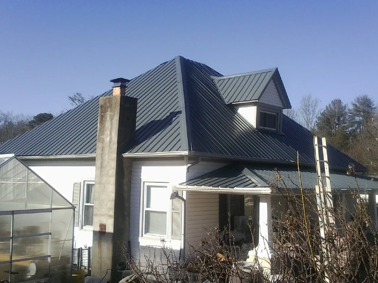 Dark blue standing seam metal roof on a white farmhouse with dormer — Slate & Tile Roof Repair by Roofing Brothers in Batavia