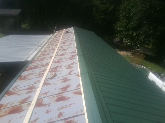Old rusted panels beside newly installed green metal roofing — Wind Damage Roof Repair by Roofing Brothers in Batavia