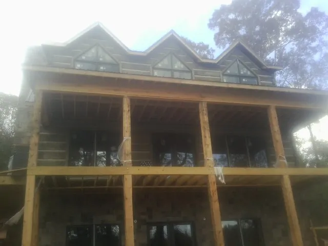 Dormers and porch framing on a large log home under construction — Roof Coating work by our crew in Batavia