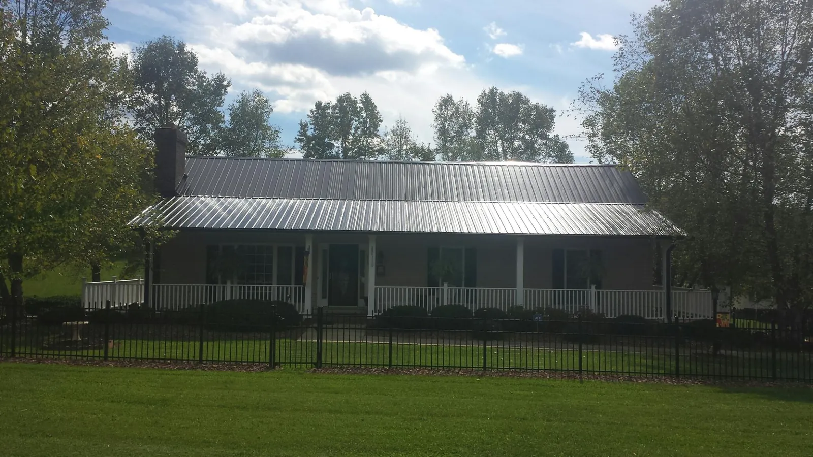 Gray metal roof on a brick ranch with a full width front porch — Gutter Guard Installation work by our crew in Batavia
