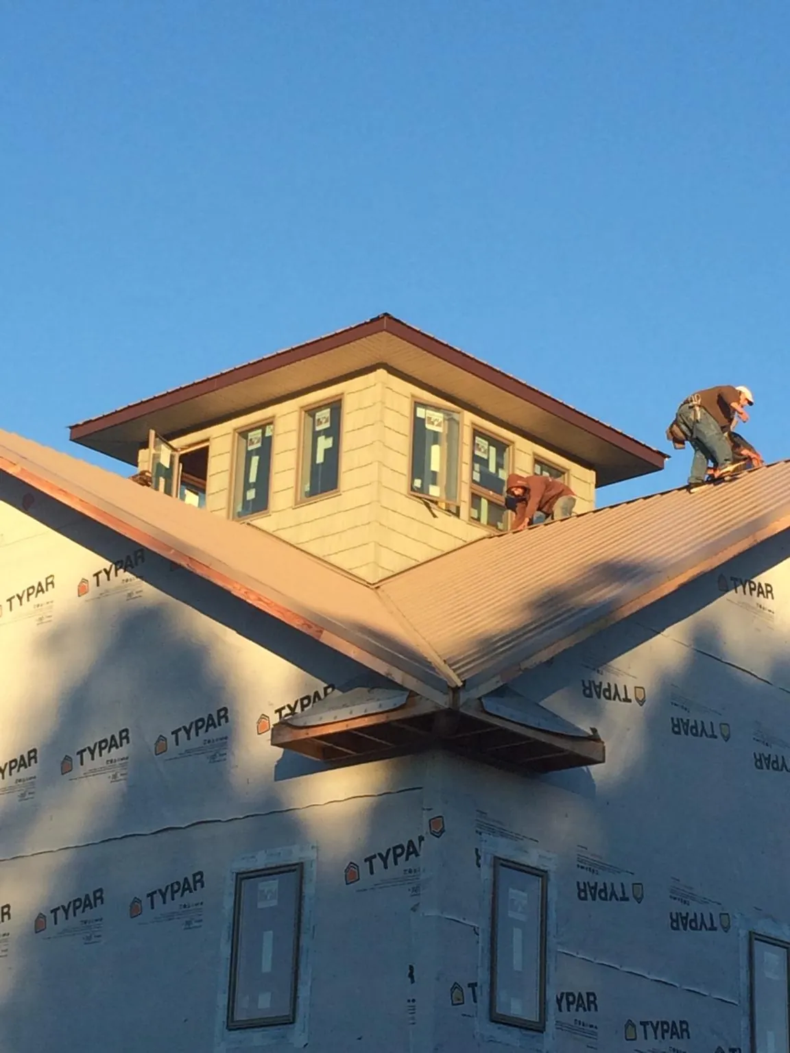 Roofers working around a rooftop cupola on a new metal roof at sunset — Roof Waterproofing in Batavia by Roofing Brothers